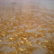 Particolare tavolo ovale in legno laccato con piano in resina bianca e trasparente con foglia oro in immersione.